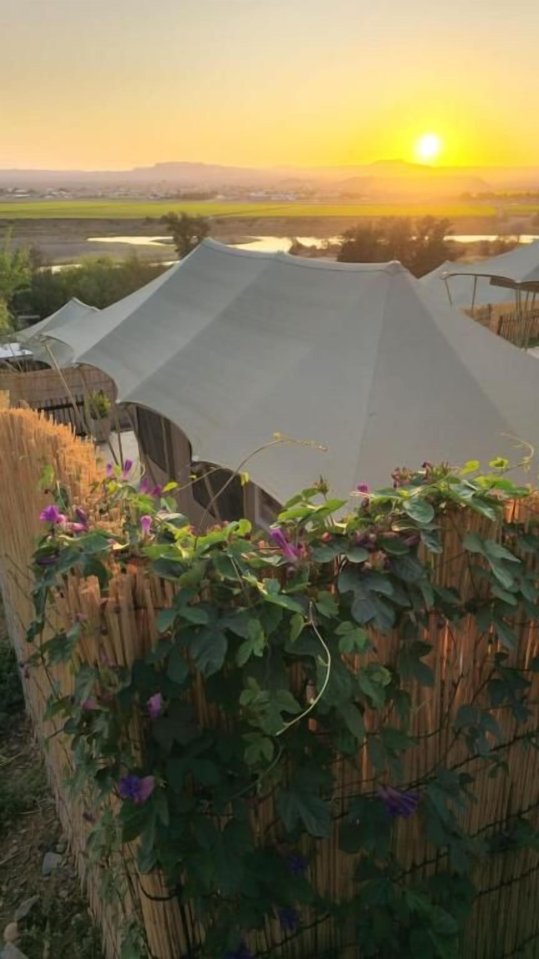 A series of tents with a view of a sunset over a landscape.
