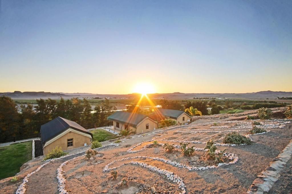 A residential area with houses, a clear sky, and the sun setting in the background.