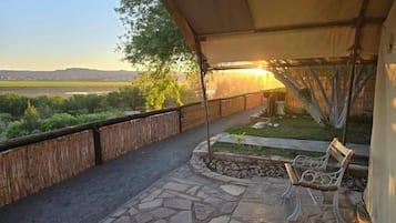 A covered outdoor seating area with a bench, a stone pathway, and a view of a natural landscape.