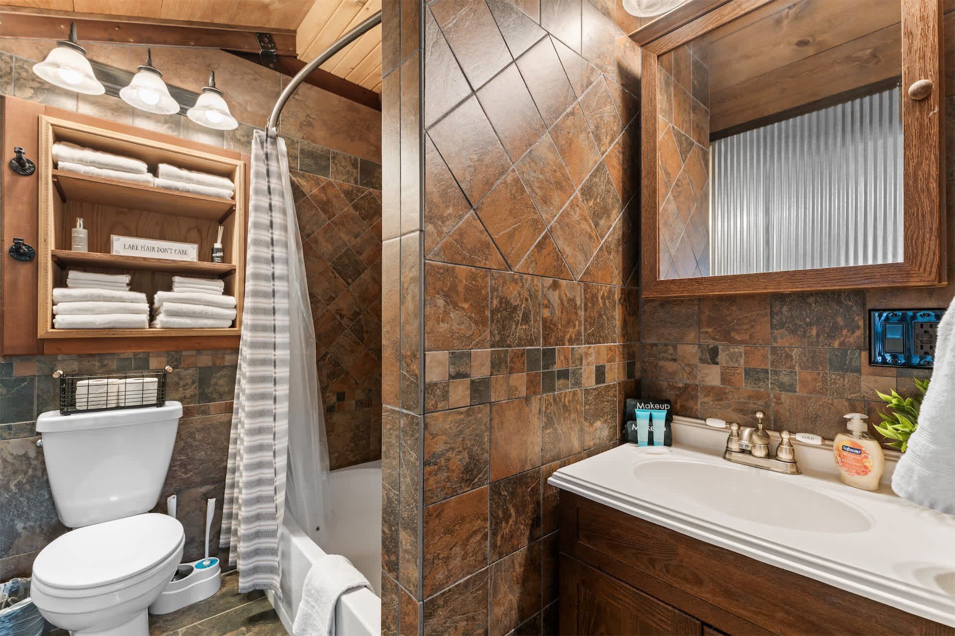 A bathroom with a shower, toilet, sink, and a vanity with a mirror.