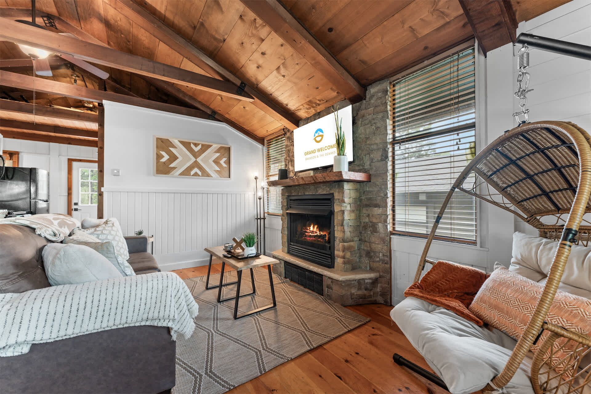A cozy room with a fireplace, a hanging chair, and a bed with a view of the outdoors.