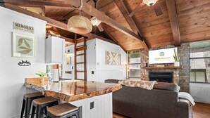 Un interior rústico con una isla de cocina, taburetes de bar, un sofá y una chimenea.