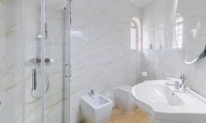 Ein modernes Badezimmer mit Duschkabine aus Glas, einem Standwaschbecken und einem großen Spiegel.