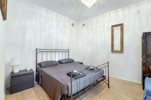 Una camera da letto con un letto, un comodino, una lampada e uno specchio a parete.