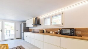 A modern kitchen with white cabinets, a built-in microwave, and a window overlooking a patio. - Resort Beach San Gemiliano (Arbatax)