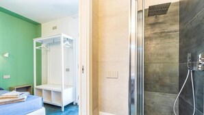 A hotel room with a bed, a walk-in closet, and a shower area. - Resort Beach San Gemiliano (Arbatax)