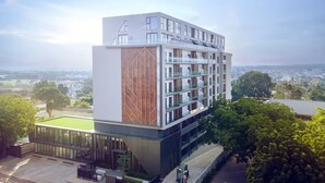 A modern multi-story building with a glass facade, a unique geometric design on the side, and a view of the surrounding cityscape. - The Lennox by Clifton Homes (Accra)