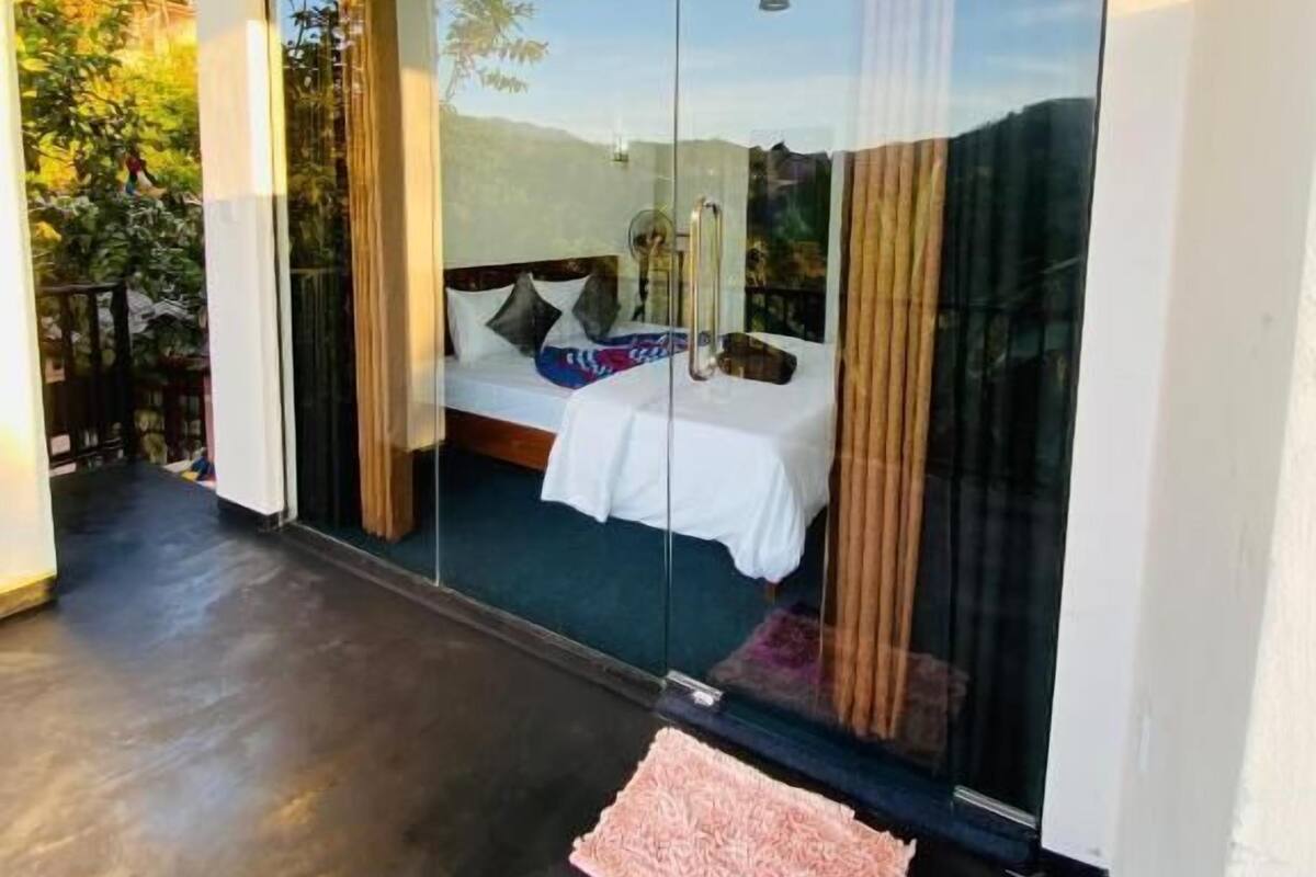 Un dormitorio con cama, puerta de vidrio y vistas al exterior.