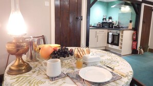 Un tavolo da pranzo con una lampada, frutta e un piatto. Si intravede una cucina sullo sfondo.