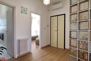A hallway with a radiator, a sliding door, and a wall with abstract art. - Casa Puccini - Cozy 2-bedroom Florentine home (Florence)