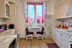 A compact kitchen with a window, two chairs, a table, and a microwave. - Casa Puccini - Cozy 2-bedroom Florentine home (Florence)