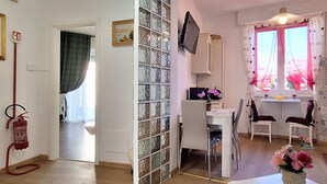 A room with a dining table, chairs, a television, and a window with curtains. - Casa Puccini - Cozy 2-bedroom Florentine home (Florence)