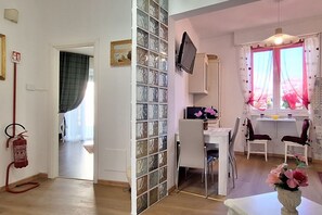 A room with a dining table, chairs, a television, and a window with curtains. - Casa Puccini - Cozy 2-bedroom Florentine home (Florence)