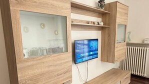 Un soggiorno moderno con arredi in legno integrati, una TV a schermo piatto e un termosifone.