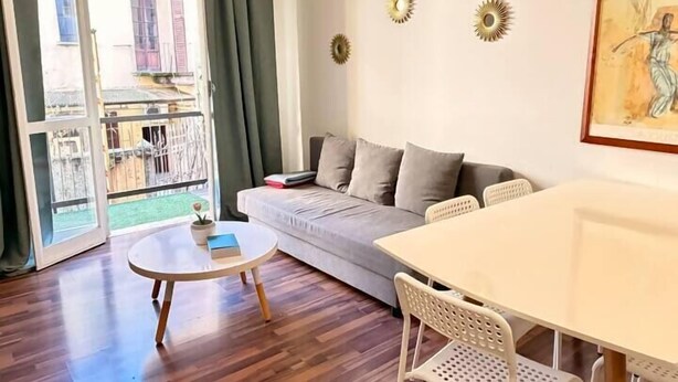 Un soggiorno moderno con divano, tavolo da pranzo, sedie e vista panoramica attraverso una porta vetrata.