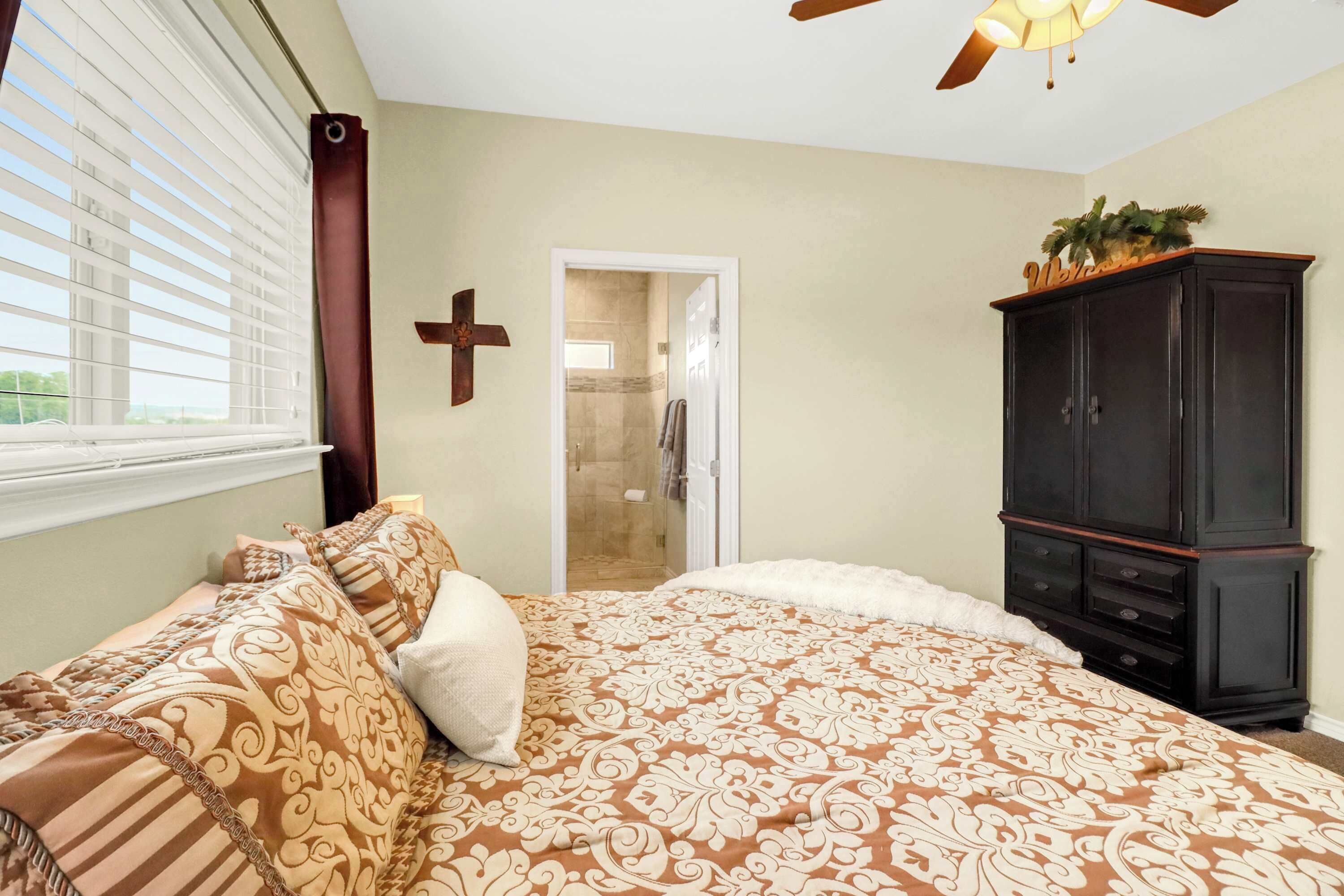 Quarto com uma cama grande, um guarda-roupa, um chuveiro e uma cruz na parede.