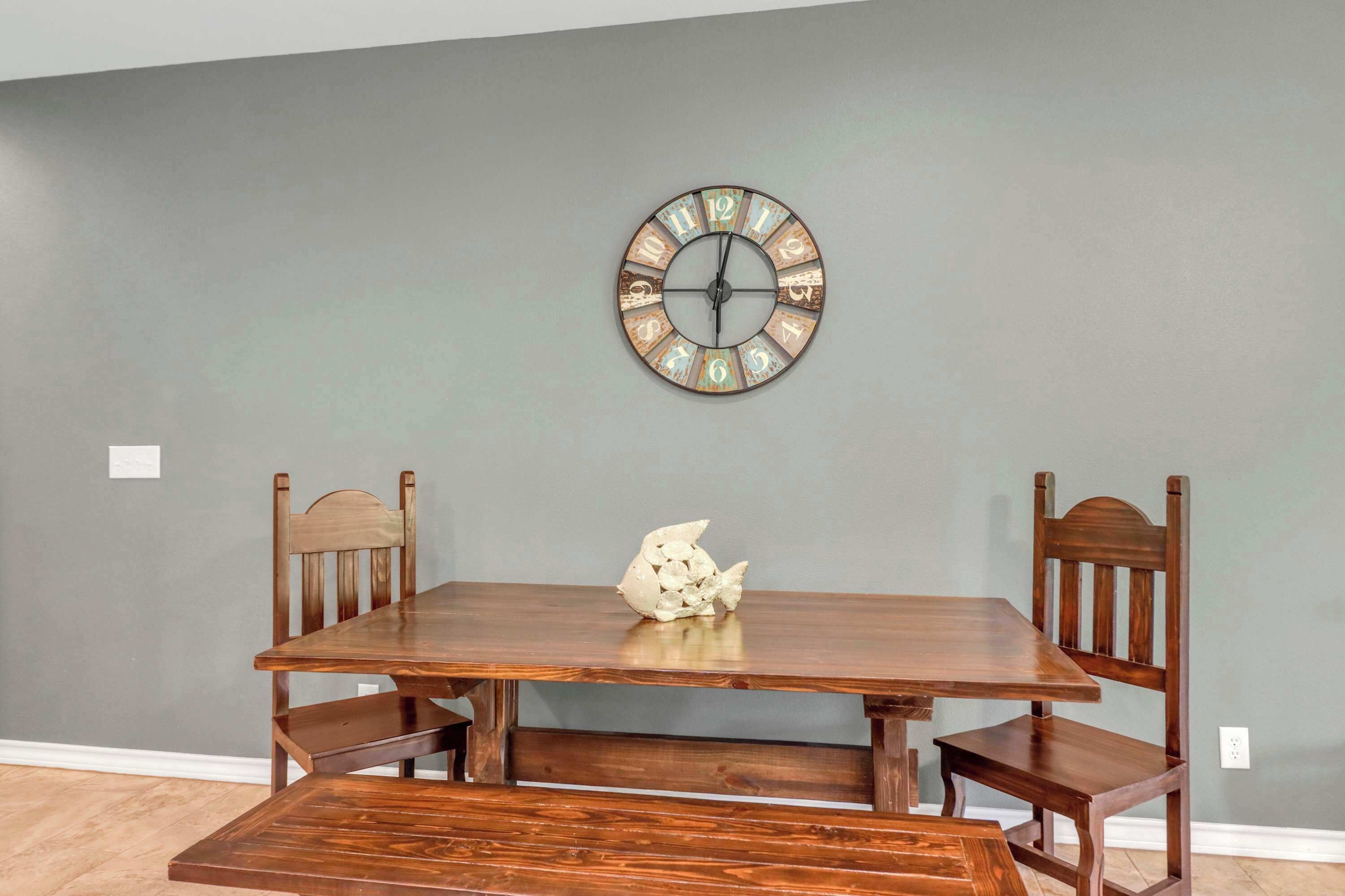 A dining table with chairs, a wall clock, and a decorative fish sculpture.