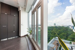 A modern apartment with large windows, a view of a cityscape, and a balcony with a plant. - TRACY SAILING TOWER (Ho Chi Minh)
