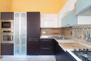A modern kitchen with stainless steel appliances, a double sink, and a gas stove. - Hostdomus - The Mistral Apartment (Alassio)