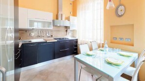 Una cocina moderna con armarios negros, una encimera blanca y un comedor con mesa y sillas de vidrio.