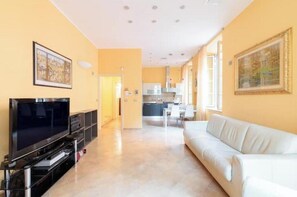 A living room with a TV, sofa, and artwork on the walls. - Hostdomus - The Mistral Apartment (Alassio)