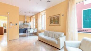 Amplia sala de estar con un sofá, una mesa de comedor y una cocina al fondo.