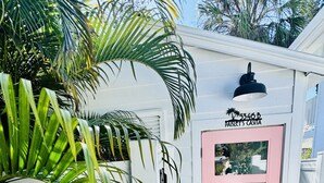 A white building with a pink door, labeled 'Paisley's Casa,' and a black outdoor light fixture above it.