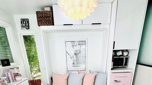 A bedroom with a bed, pillows, a map, a microwave, and a trash can.
