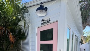 A house with a pink door, a small porch, and a palm tree.
