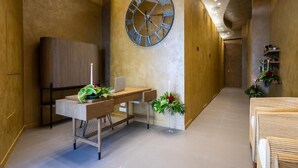 A modern hotel lobby with a wooden reception desk, a large wall clock, and a seating area with plants. - B&B Relax Assoluto - Luxury Urban Spa (Casalbordino)