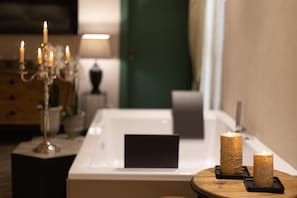 A bathroom with a bathtub, a mirror, a wooden side table with candles, and a candelabra. - B&B Relax Assoluto - Luxury Urban Spa (Casalbordino)