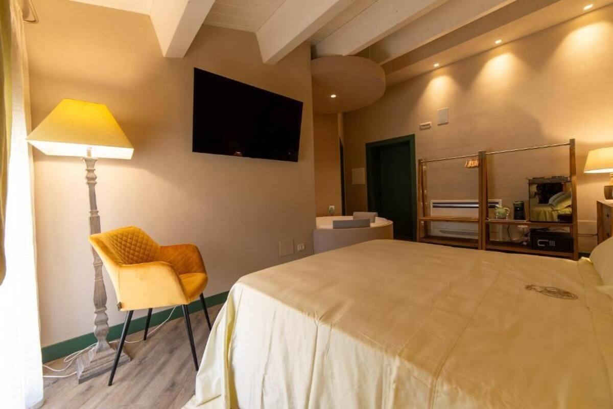 A hotel room with a bed, a chair, a TV, and a desk with a mirror.