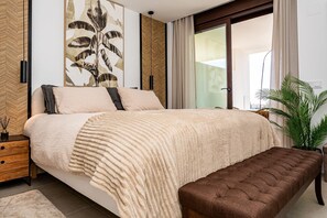Ein Schlafzimmer mit einem Bett, Nachttisch, Bank und einer großen Pflanze.