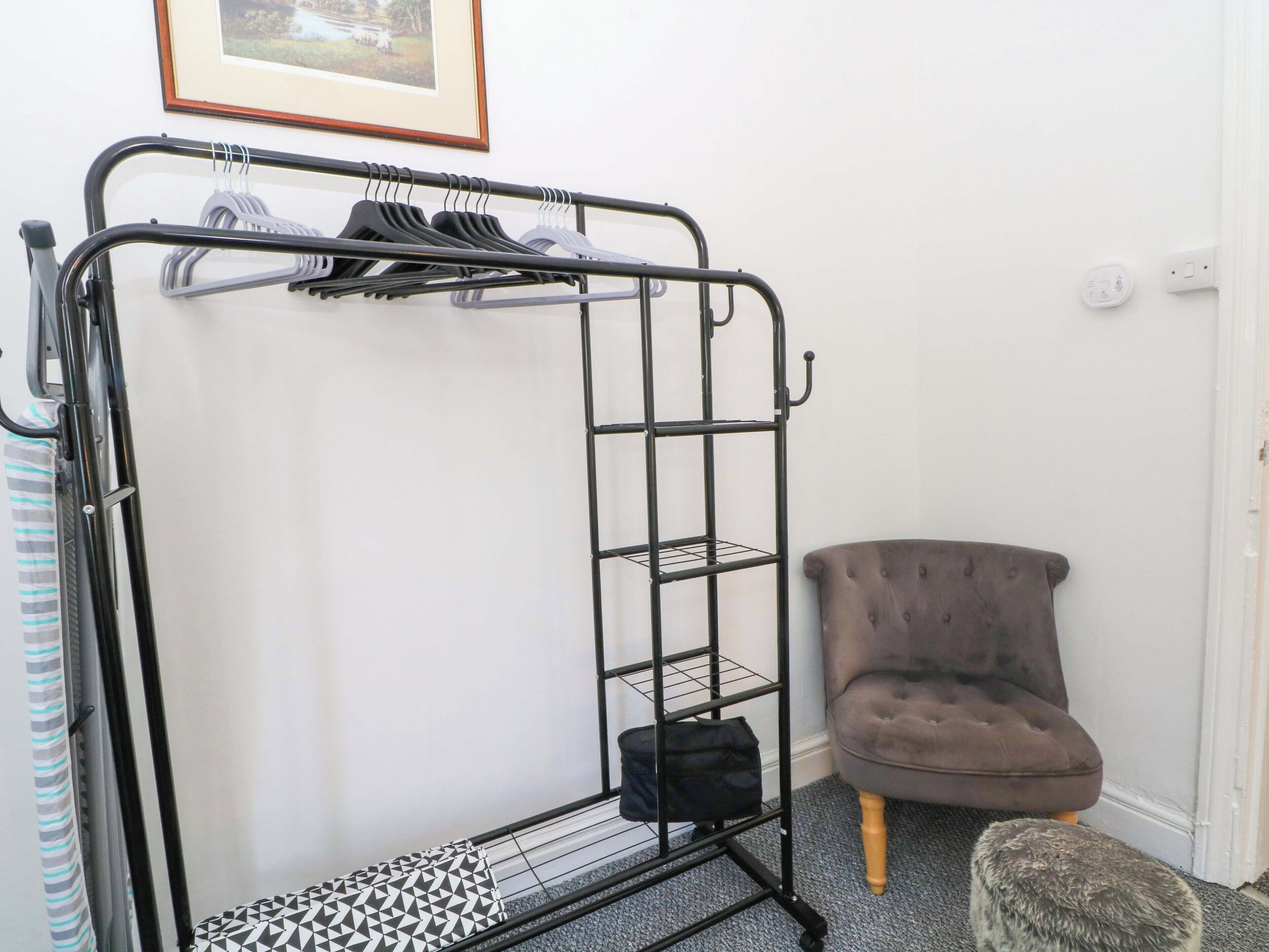 A bunk bed with a metal frame, a grey upholstered chair, and a small ottoman.
