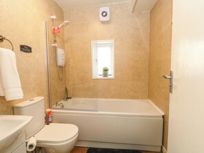 A bathroom with a bathtub, toilet, and a small window with a plant. - 4 Newton Terrace (Lancaster)