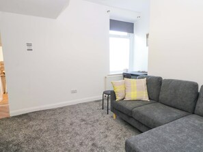 A modern living room with a grey sofa, a small table, and a window with blinds. - 4 Newton Terrace (Lancaster)