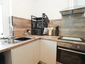 A kitchen with a sink, stove, and microwave. There are utensils and a coffee maker on the counter. - 4 Newton Terrace (Lancaster)
