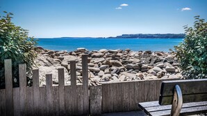A wooden bench with a view of a rocky beach and calm sea.
