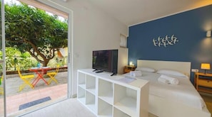 Una camera da letto con un letto, una televisione, una scrivania e vista su un albero.