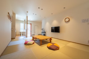 Habitació amb esteves de tatami, una taula de fusta i coixins.