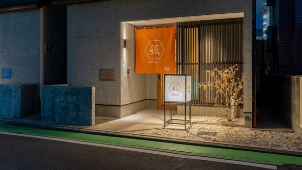 A building entrance with a sign reading 'KITSUNE,' a small potted plant, and a concrete bench. - Irodori Hotel KITSUNE (fukuokashi,hakataku,minoshima)