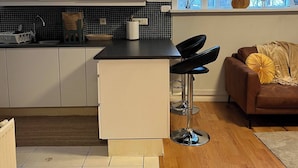 A modern kitchen with white cabinets, a black countertop, and a window with a view of trees. - 2 Bedroom Condo With Cheap Pick up Services (Reykjavik)