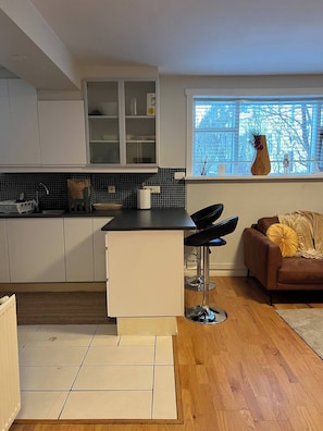 Eine moderne Küche mit weißen Schränken, einer schwarzen Arbeitsplatte und einem Fenster mit Blick auf Bäume.