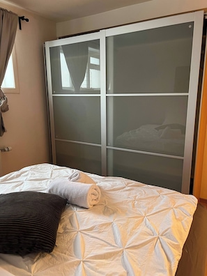 Ein Hotelzimmer mit einem Bett, einem großen Schiebeglastürenschrank und einem Vorhangfenster.