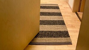A hallway with a wooden door, a striped rug, and a framed picture on the wall. - 2 Bedroom Condo With Cheap Pick up Services (Reykjavik)
