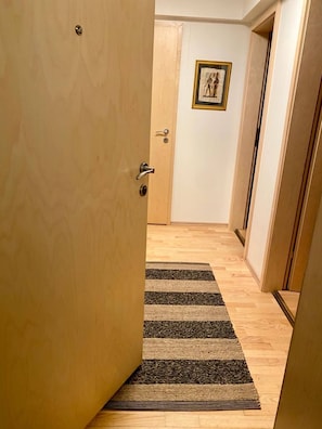 Ein Flur mit Holztür, StreifenTeppich und einem gerahmten Bild an der Wand.