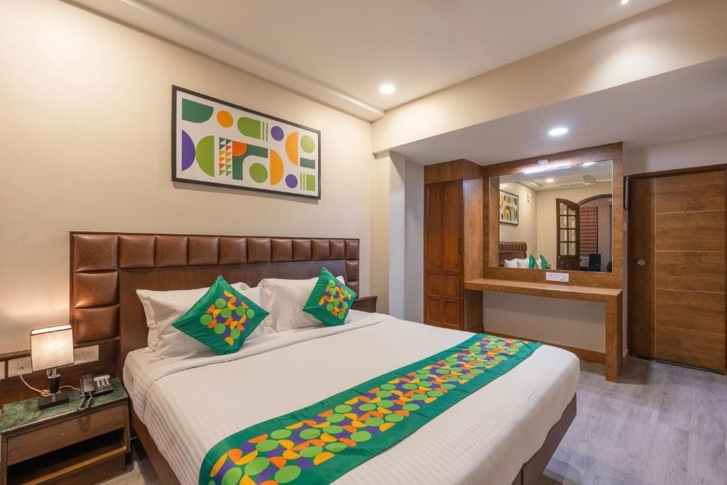 Une chambre d’hôtel avec un lit, une table de chevet, un miroir et une armoire en bois.