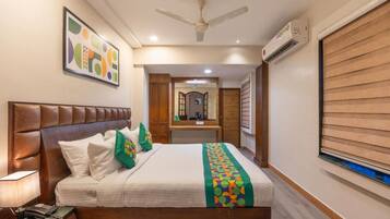 A hotel room with a bed, a nightstand, a ceiling fan, an air conditioning unit, and a wooden wall panel.