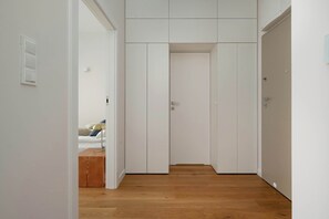 A hallway with a wooden floor, white walls, and a closed door at the end. - Luxury Apartment with Parking | Air Conditioning | Near the Market Square (Wrocław)