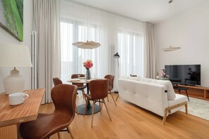 A modern living room with a sofa, dining table, chairs, and a TV. - Luxury Apartment with Parking | Air Conditioning | Near the Market Square (Wrocław)
